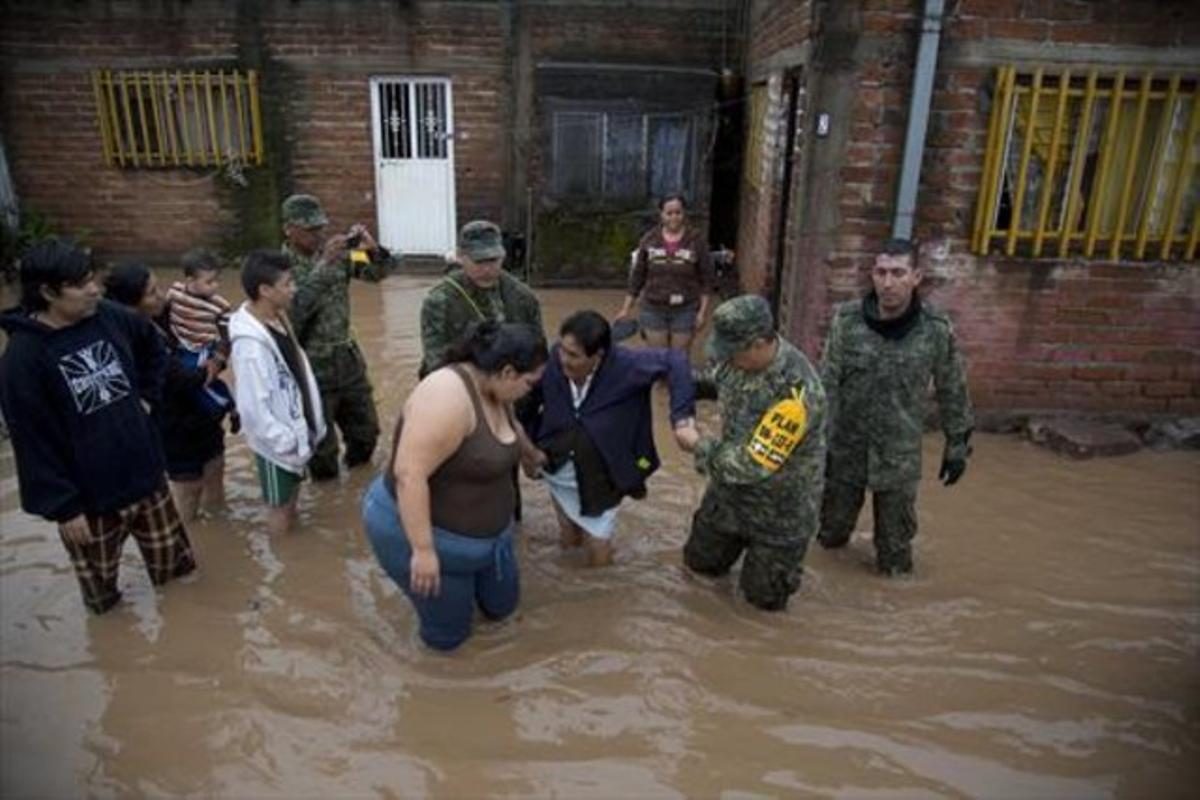 Uns soldats ajuden una dona a sortir de casa seva, inundada, per portar-la a un refugi, ahir.