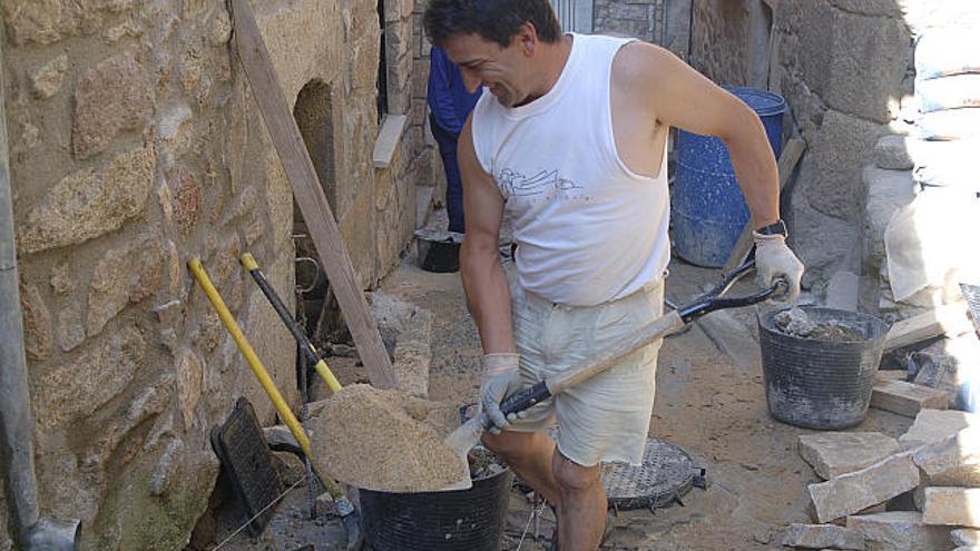 Un trabajador transporta arena en uno de los puntos de la calle El Guapo, que es pavimentada con piedra tradicional.