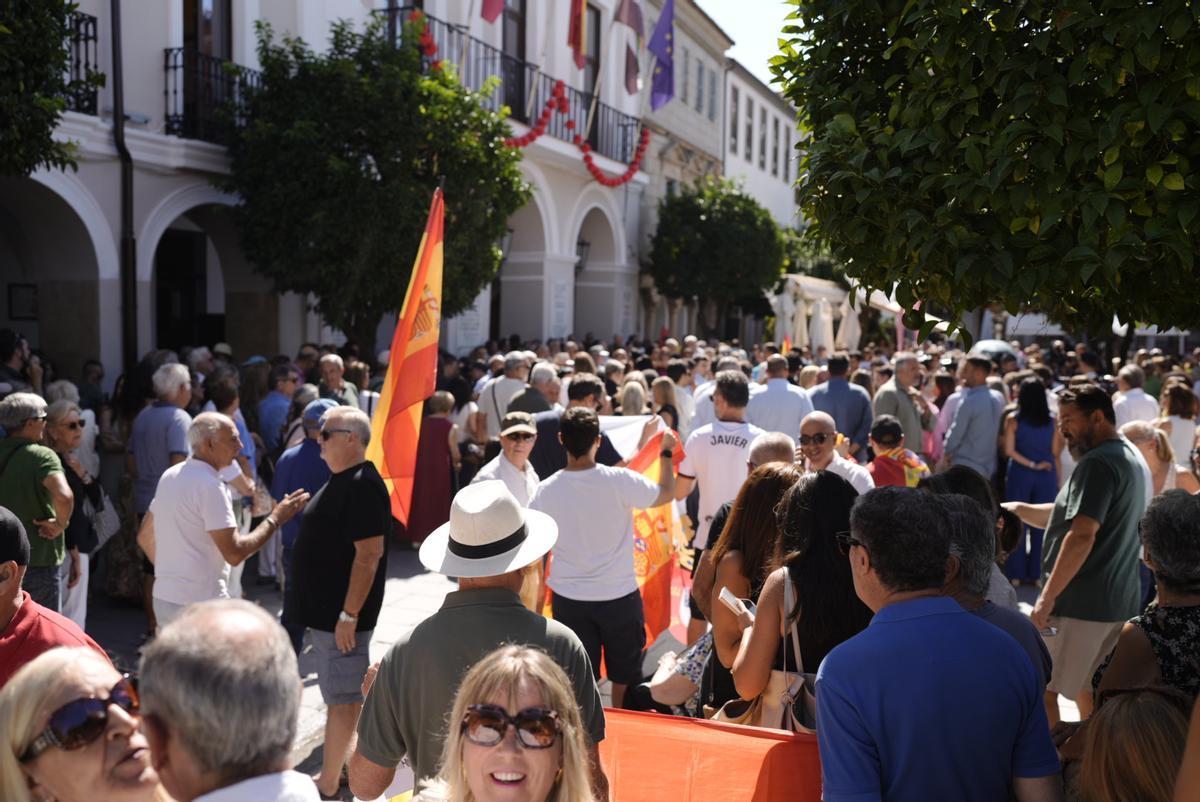 Vecinos y representantes públicos se reúnen ante el Ayuntamiento de Mérida entre banderas de España y Ceuta para mostrar su respaldo a la ciudad autónoma.