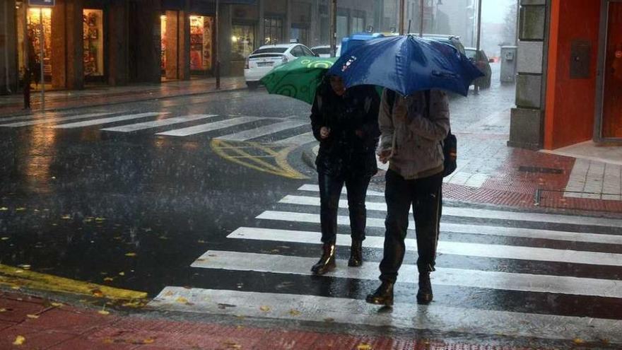 Dos peatones se protegen de la lluvia en la ciudad. // Rafa Vázquez