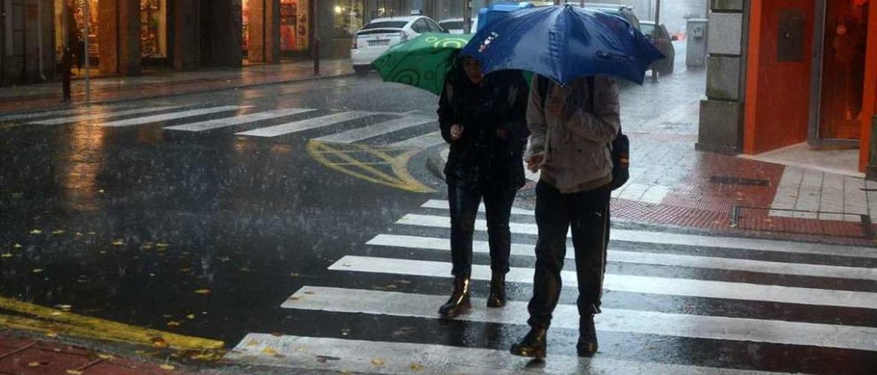 Dos peatones se protegen de la lluvia en la ciudad. // Rafa Vázquez