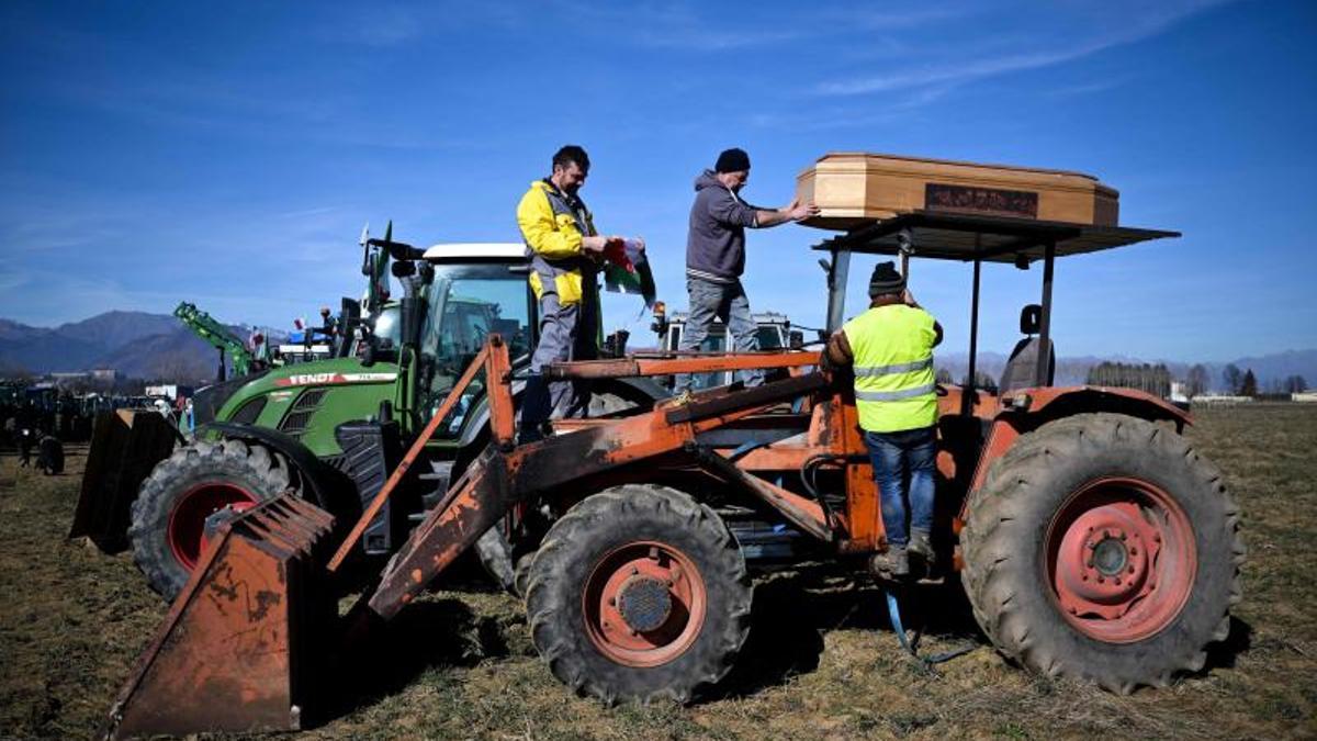 Los agricultores colocan un ataúd en un tractor junto a la carretera durante una manifestación cerca de la autopista en Rivoli, cerca de Turín, el 5 de febrero de 2024.