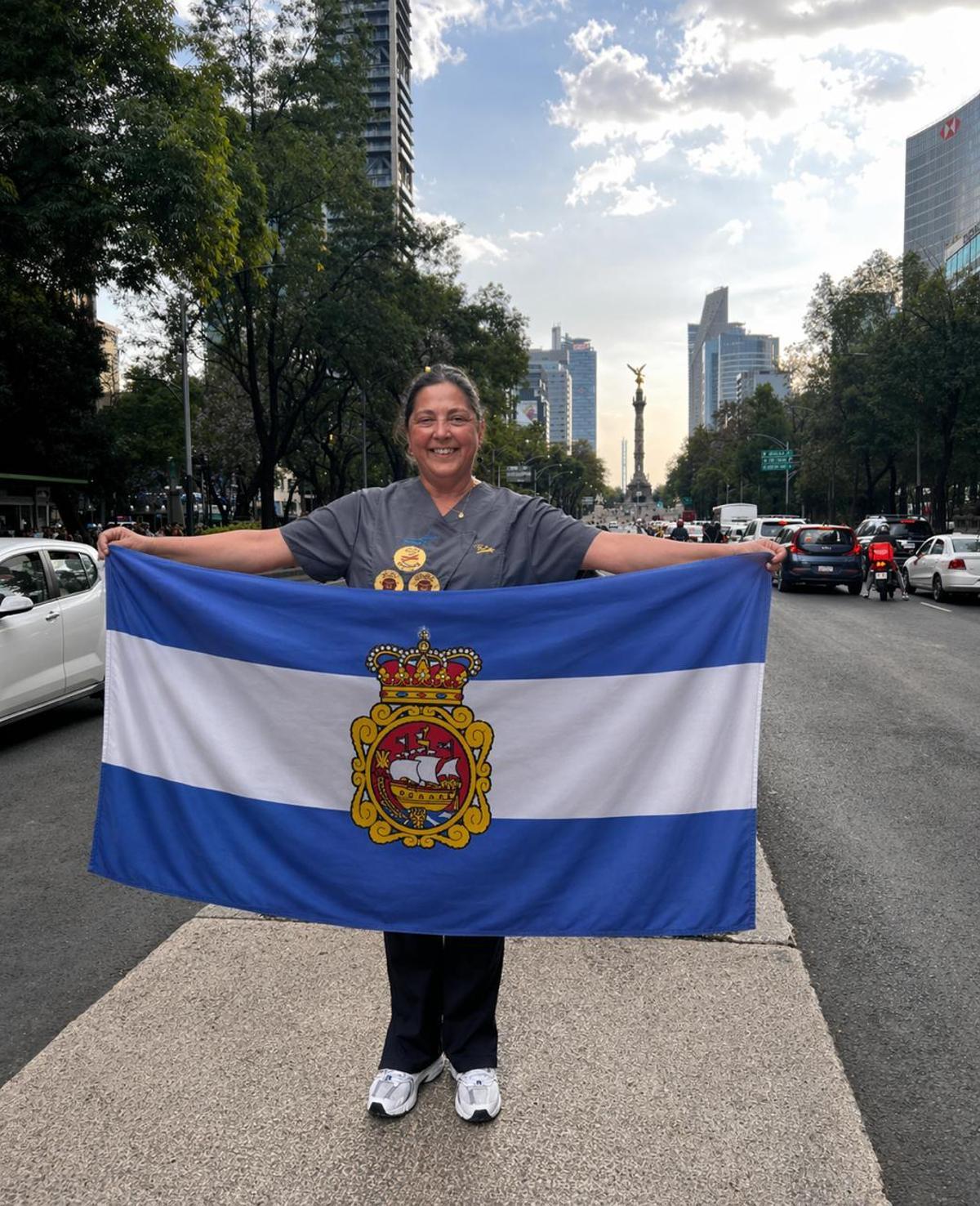 Pilar Meana posando con la bandera de Avilés en una calle de Ciudad de México.