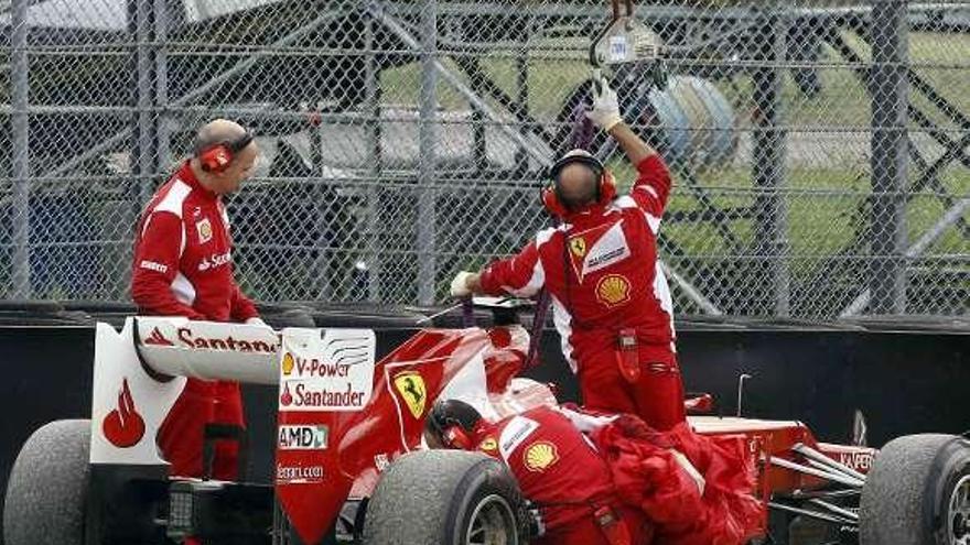 Los mecánicos retiran el coche de Alonso. / alessandro bianchi / reuters