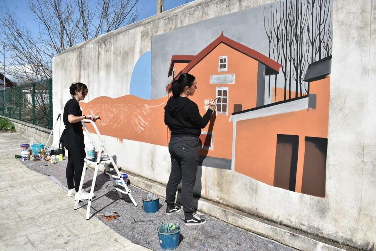 Dos de las artistas participantes durante la elaboración de una pintura mural.