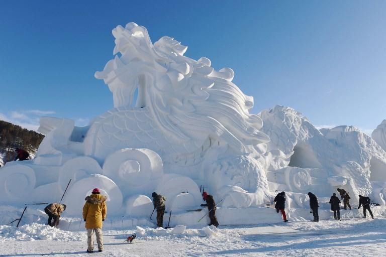Trabajadores crean una escultura de hielo y nieve en forma de dragón, en preparación para la temporada turística de invierno en Mohe, en la provincia china de Heilongjiang. - La región, situada al noreste de China, soporta temperaturas tan bajas como 40 grados bajo cero en invierno. Photo by STR / AFP