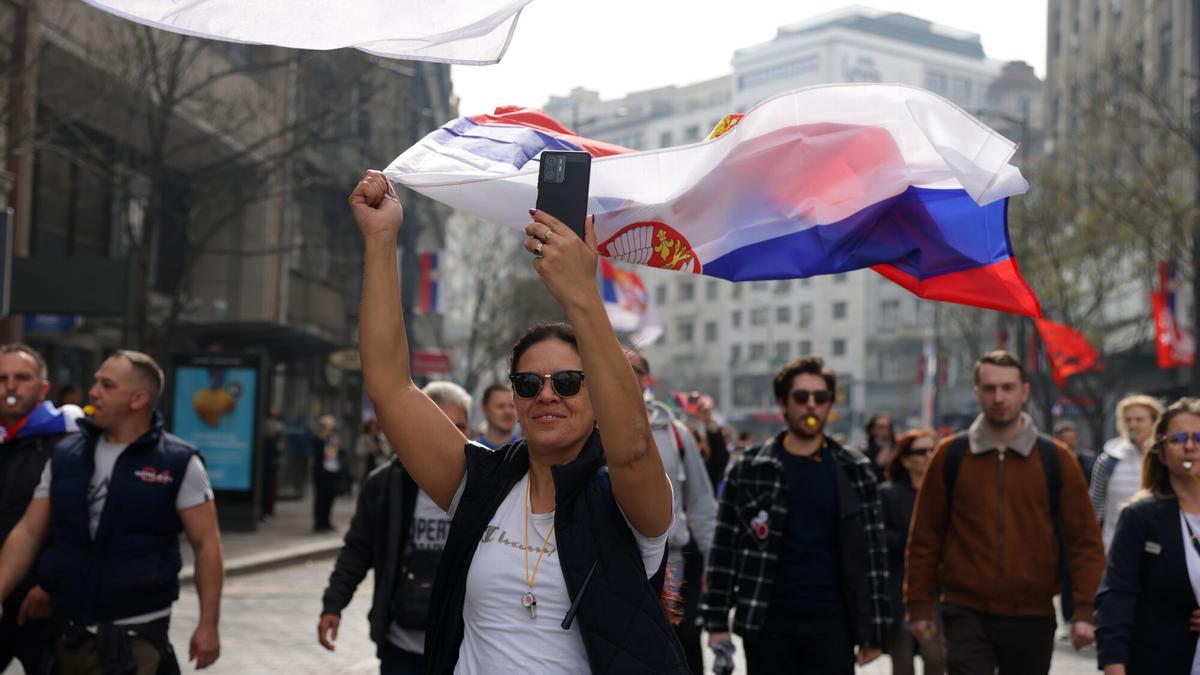 Una manifestante ondea una bandera serbia por las calles de Belgrado, camino de la manifestación de este sábado.