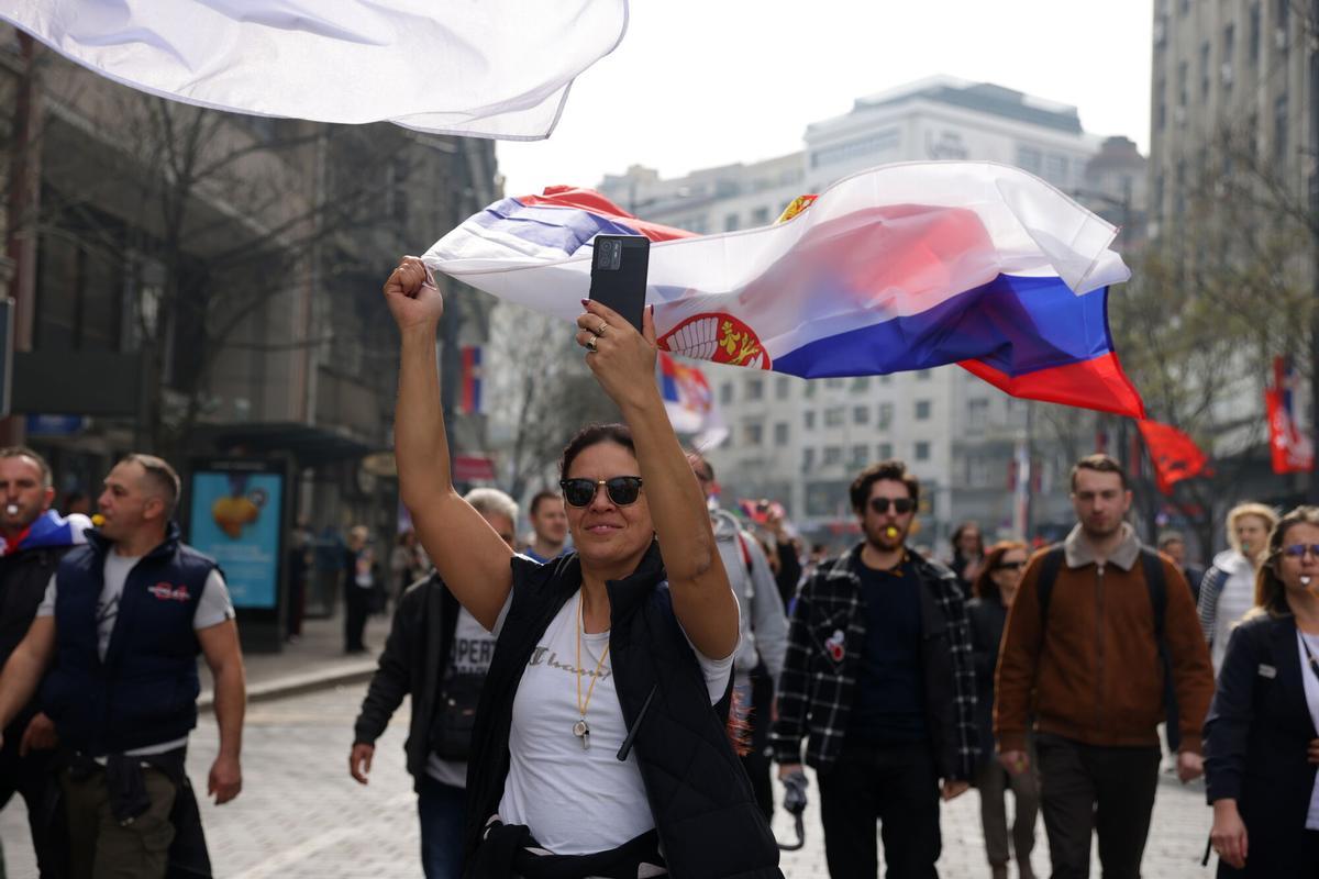 Una manifestante ondea una bandera serbia por las calles de Belgrado, camino de la manifestación de este sábado.