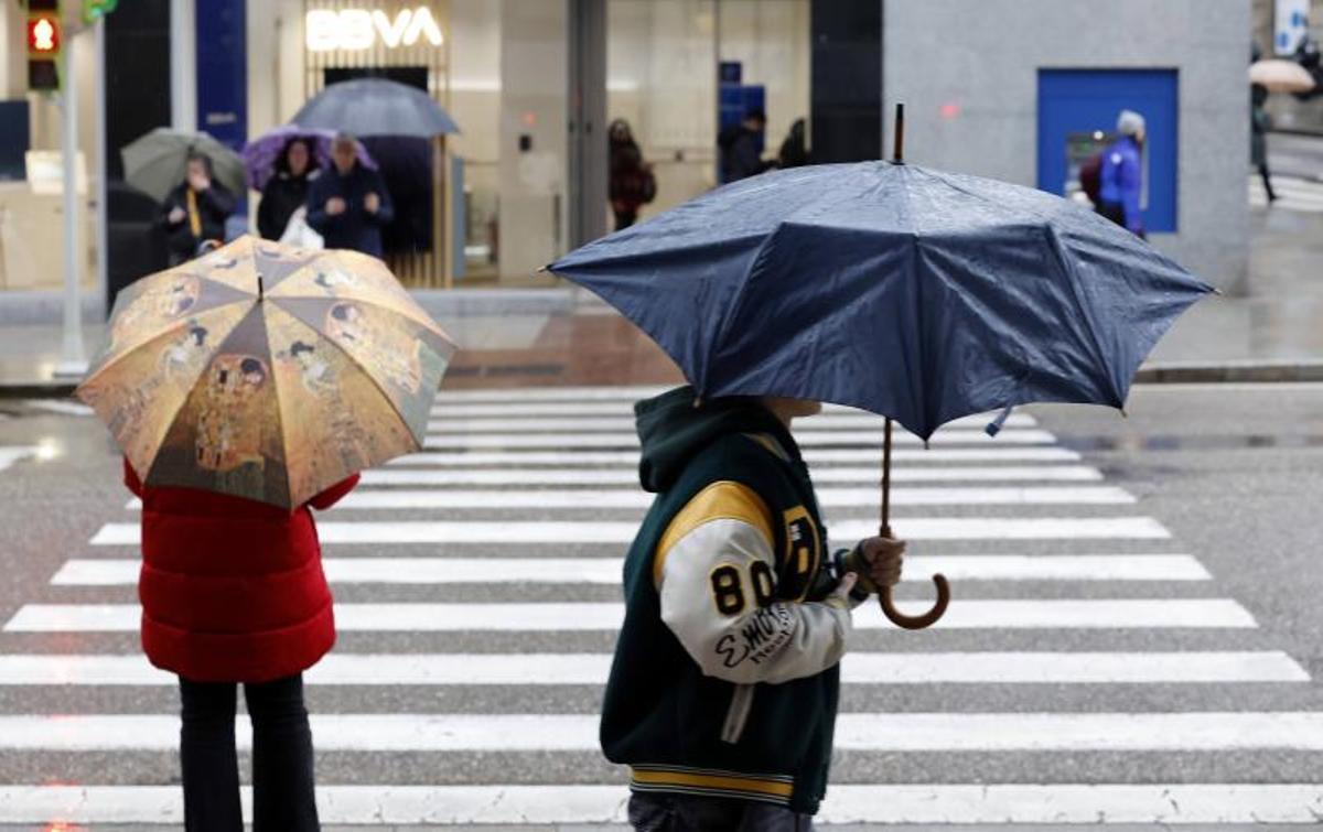 Dos viandantes con paraguas.