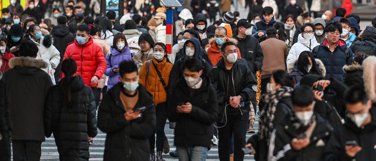 People walk on a pedestrian crossing on a street in the Huangpu district in Shanghai on January 16, 2023.