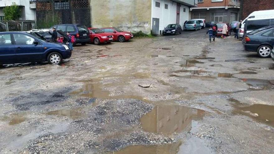 Charcos y lama, en primer plano, en el solar junto al centro educativo para el que Móvete pide mejoras.