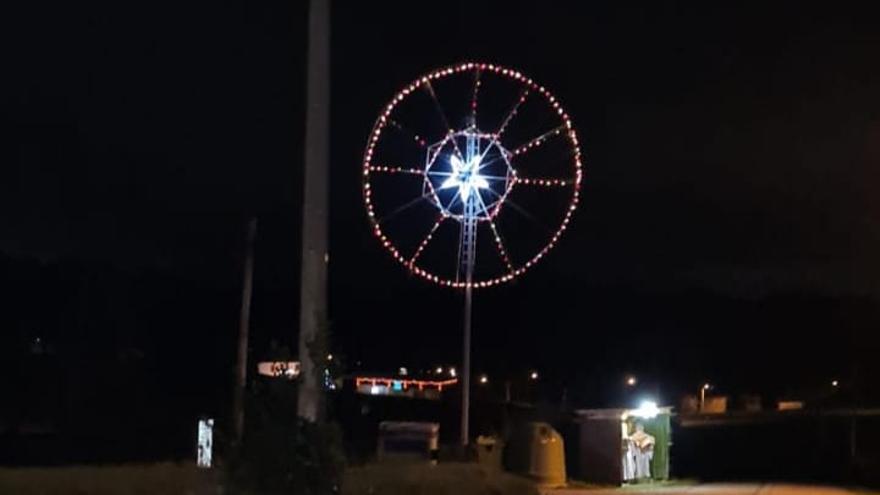 Noria de luces instalada por los vecinos y, a sus pies, el belén instalado en una marquesina de bus