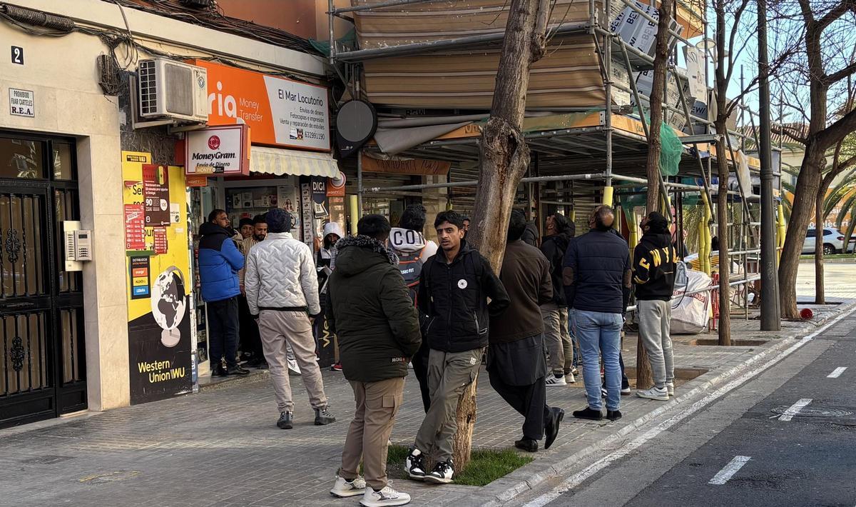 Un grupo de inmigrantes hace cola en un locutorio de la calle Burgos de València para fotocopiar documentación, ayer.