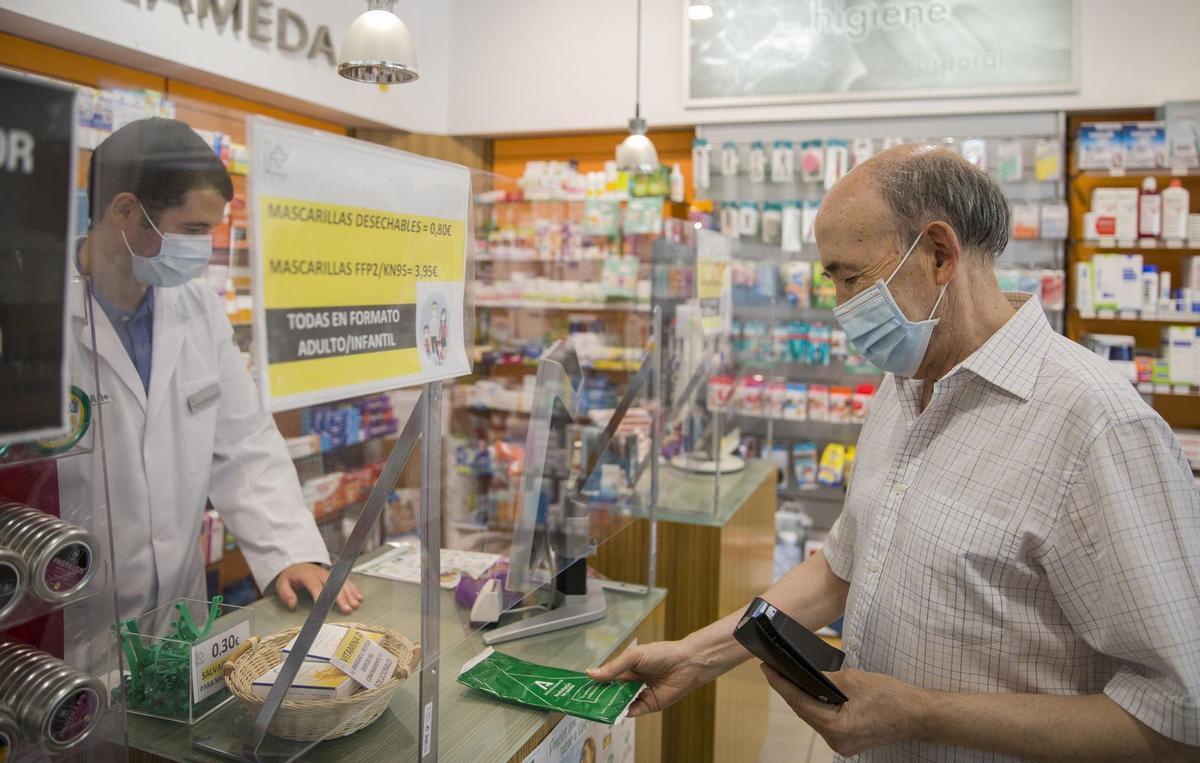 Un hombre adquiere mascarillas en una farmacia.