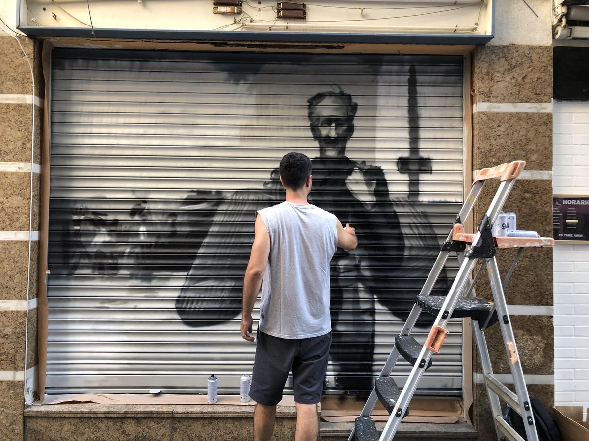 Pau Marinel·lo treballant en el primer mural, situat al número 87 del carrer Trinitat.