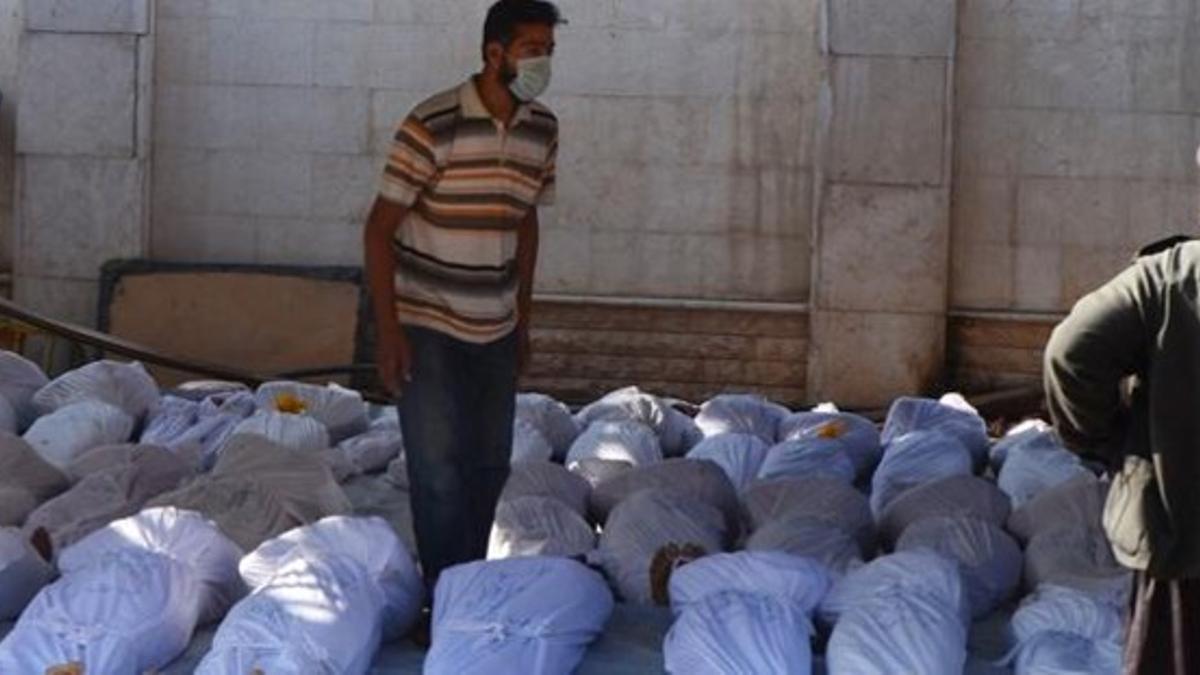 Un activista sirio inspecciona los cuerpos de decenas de muertos en el ataque, en la región de Guta, este miércoles.