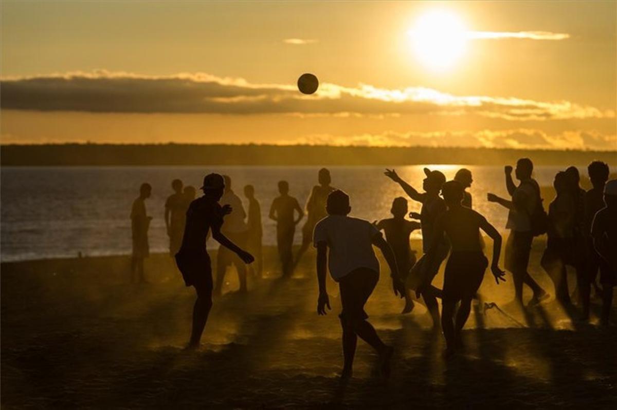 Un grupo de jovenes juegan a fútbol en la playa de Ponta Negra, en Manaos.