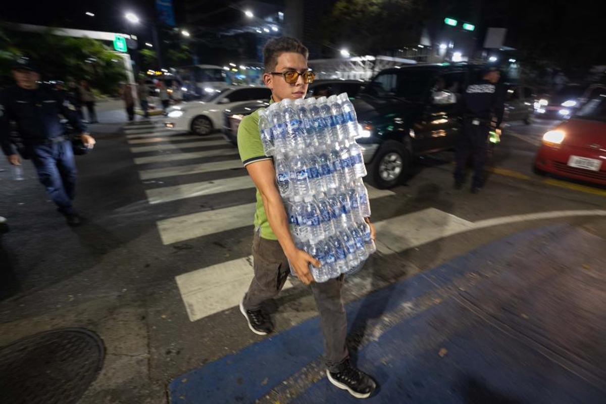 Un joven carga con un lote de agua para las víctimas de los terremotos.