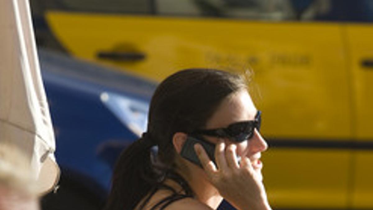 Una chica habla por teléfono móvil, en una terraza de Barcelona.