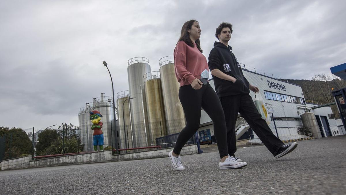 Dos jóvenes pasan ante la fábrica de Danone en Salas. | Miki López