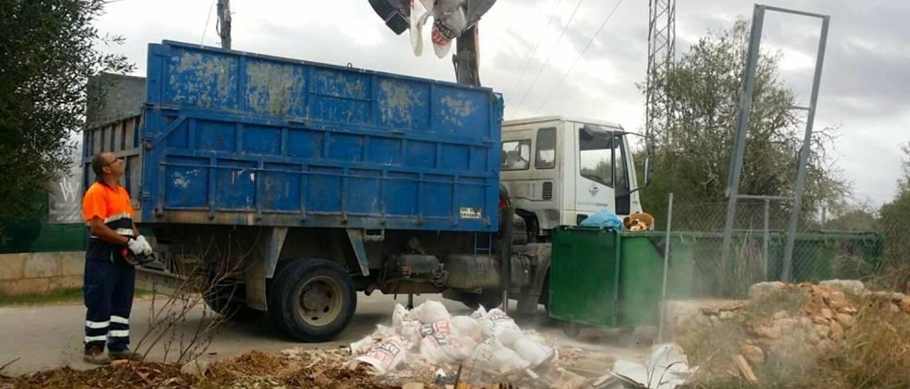 Un camión de la empresa de limpieza recoge residuos en suelo rústico.