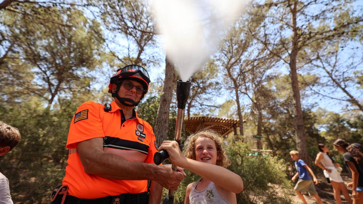 Una niña usando la manguera junto con un responsable de Protección Civil de Sant Antoni.
