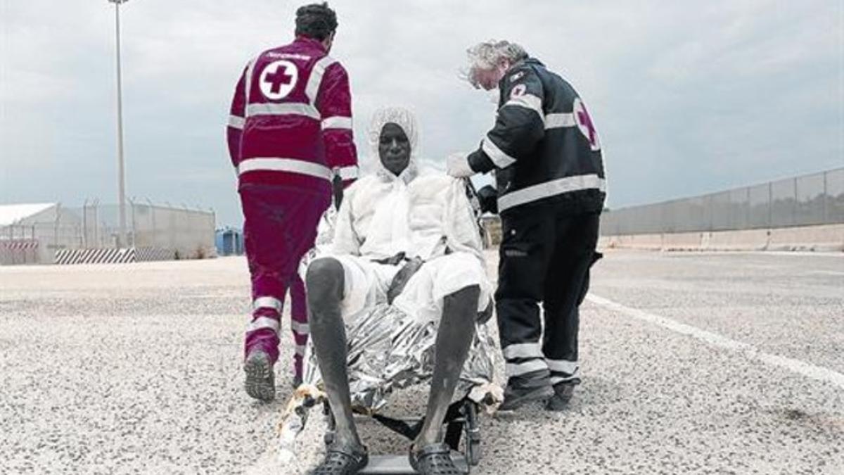 Miembros de la Cruz Roja atienden a un inmigrante tras desembarcar en Augusta (Sicilia), el pasado domingo.