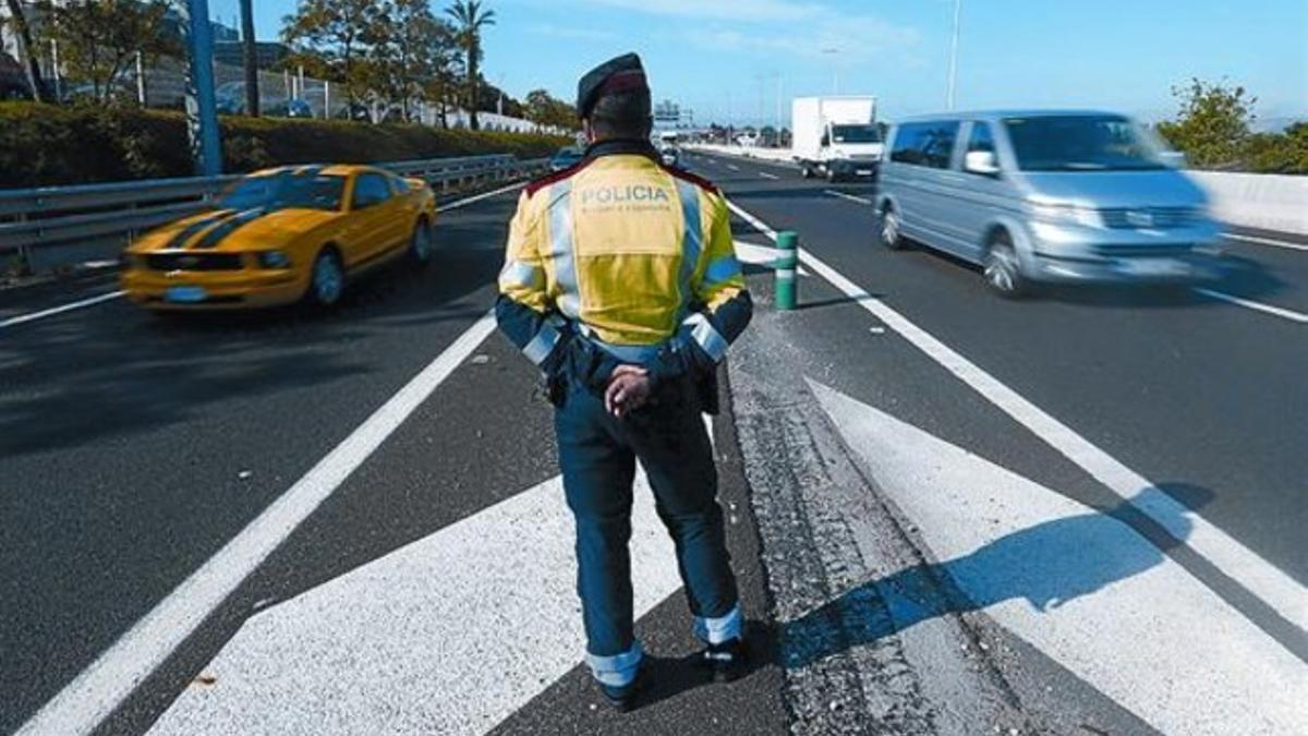 8.000 AGENTES DE TRES CUERPOS 3 Arriba, un policía inspecciona el subsuelo del hotel Arts. Abajo, un mosso en un control viario. A la derecha, policías en los alrededores del hotel Arts.