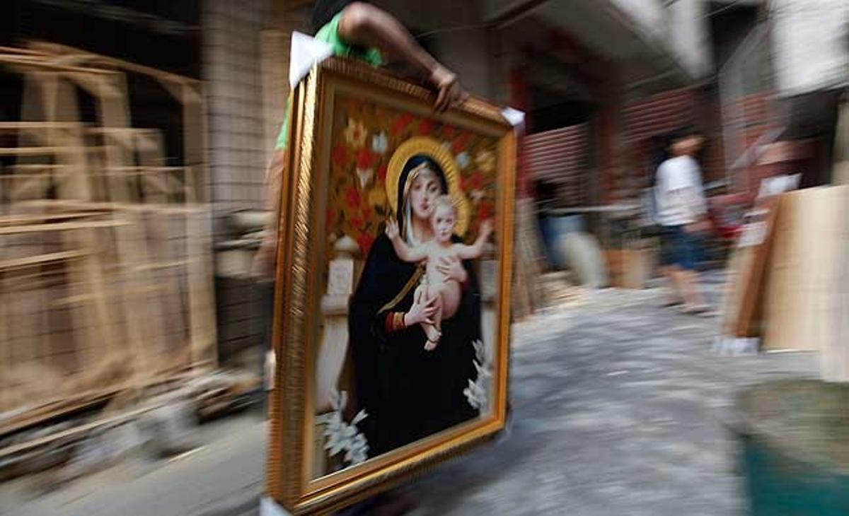 Un treballador d’una companyia de logística carrega una pintura a l’oli per empacar-la a Shenzhen (Xina).