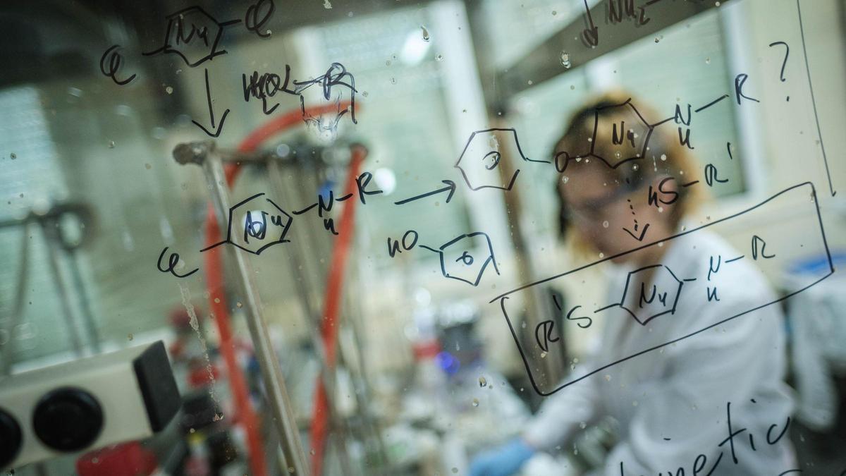 Una investigadora realiza cálculos químicos en una pizarra.