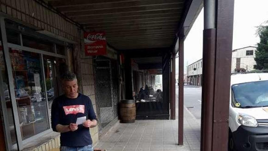 Manuel Suárez, con uno de los pasquines que encontró a la puerta de su establecimiento, en Vega de Arriba.