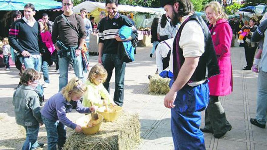 Arriba, dos pequeñas, preparando un condimento en la feria de Llanera. A la izquierda, una niña, de paseo encima de un poni.