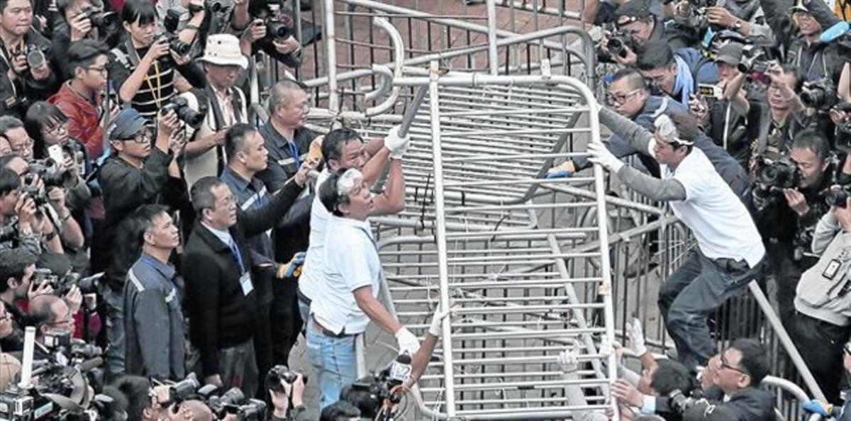 El desmantellament 8 Un grup de treballadors retira les barricades a prop de la seu governamental de Hong Kong, ahir.