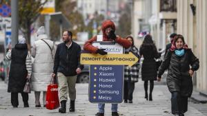 Un hombre anuncia una tienda de reparación de smartphones en una calle del centro de Moscú.