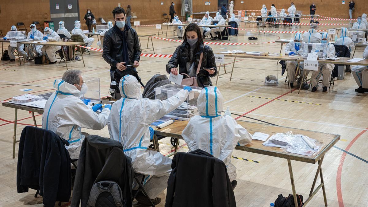 Votación con los miembros de la mesa con los epis puestos, en el Pabellón Esportiu de la Espanya Industrial.