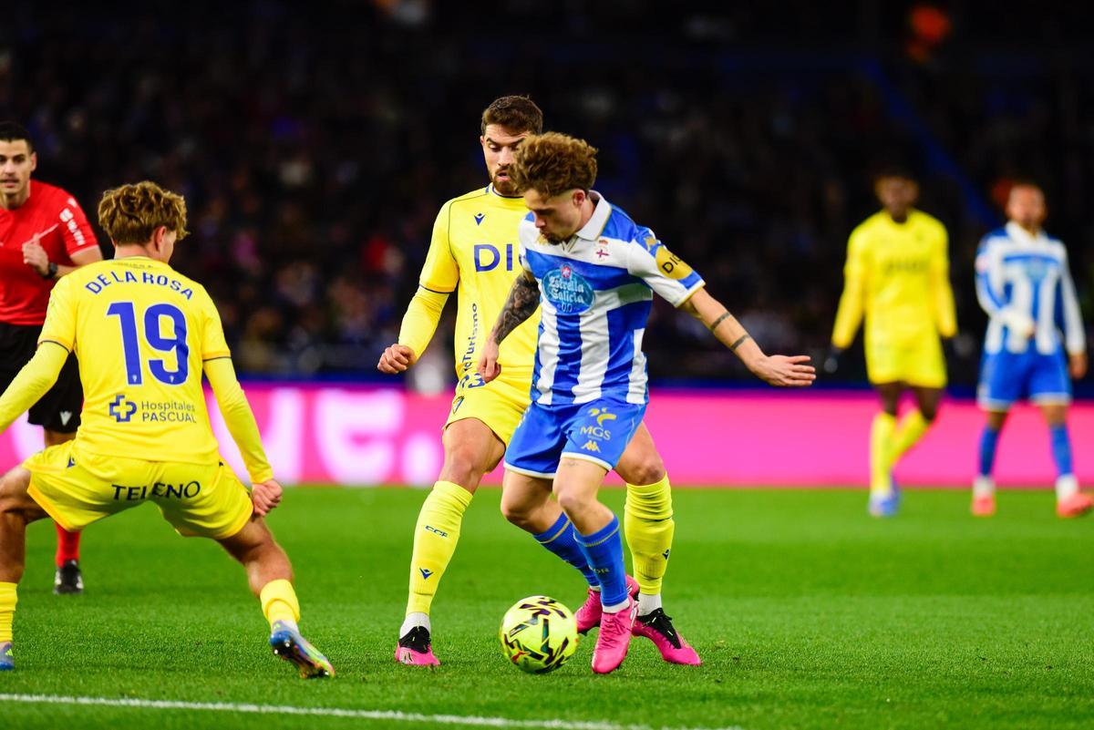 Mario Soriano controla el balón encimado por dos jugadores del Cádiz.