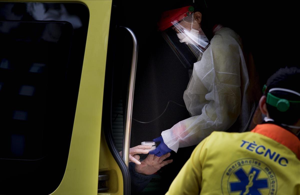 Médicos del SEM atienden a un paciente con síntomas de Covid-19 en Nou Barris, poco antes de trasladarlo al Hospital de la Vall d’Hebron.