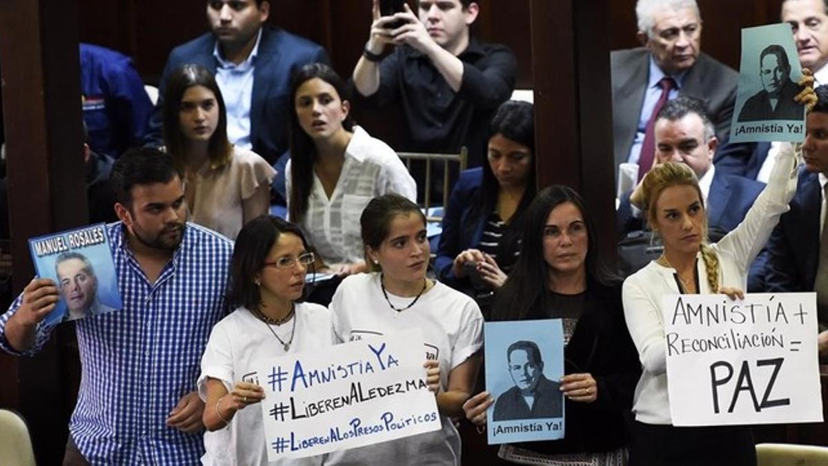 Diputados antichavistas, entre ellos Lilian Tintori (derecha), esposa del opositor encarcelado Leopoldo López, sostienen carteles a favor de la amnistía de los disidentes, en Caracas, este martes.