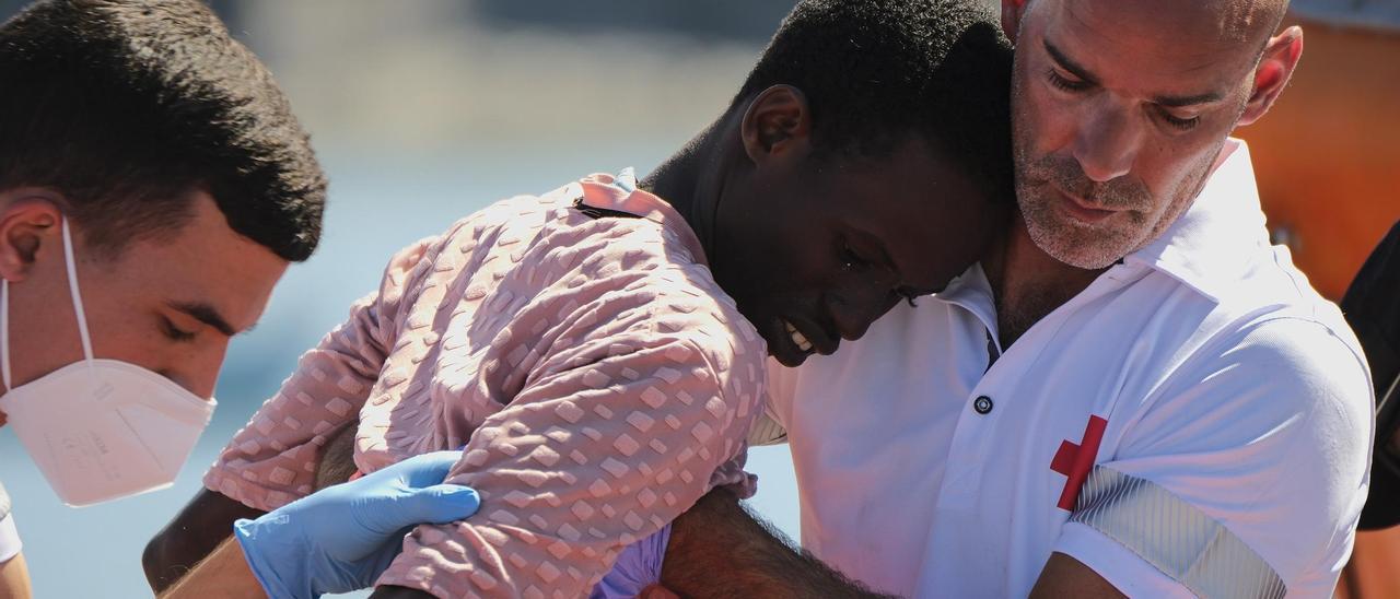 Dos voluntarios de Cruz Roja ayudan a un migrante que desembarcó en el sur de Gran Canaria.
