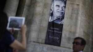 Una dona fotografia el seu marit davant d’un cartell de Gabo al palau de Belles Arts de Mèxic.