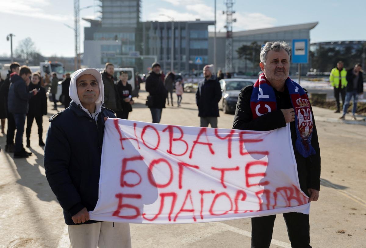 Fans del tenista sostienen una pancarta en la que puede leerse ’Dios te bendiga, Novak’, mientras le esperan en el aeropuerto de Belgrado.