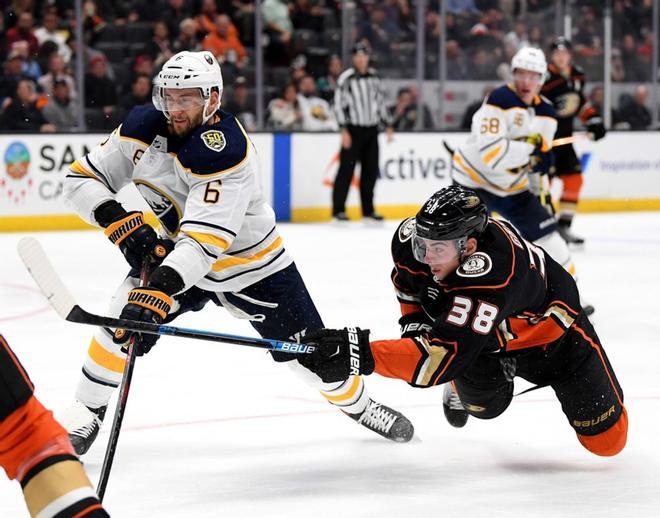 Derek Grant # 38 de los Anaheim Ducks cae mientras toma un tiro frente a Marco Scandella # 6 de los Buffalo Sabres durante el tercer período en una victoria de 5-2 Ducks en el Honda Center.