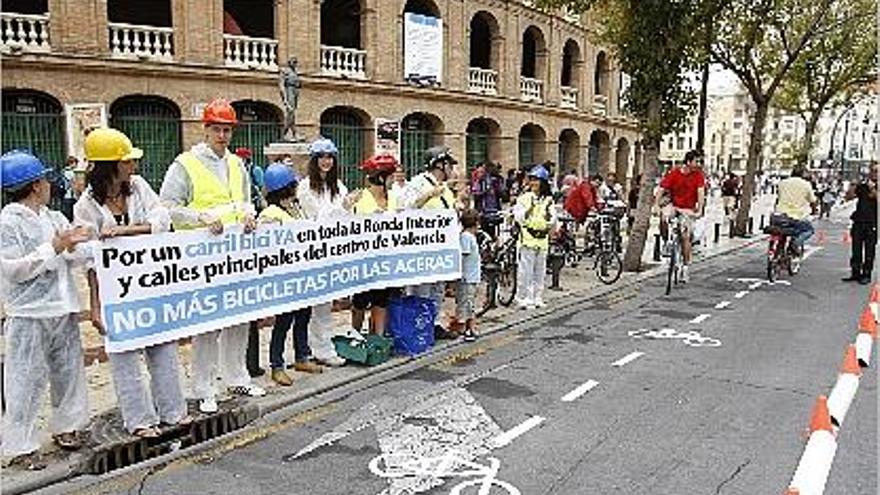 Miembros de Valencia en Bici simulan la instalación de un carril bici en la calle Xàtiva.