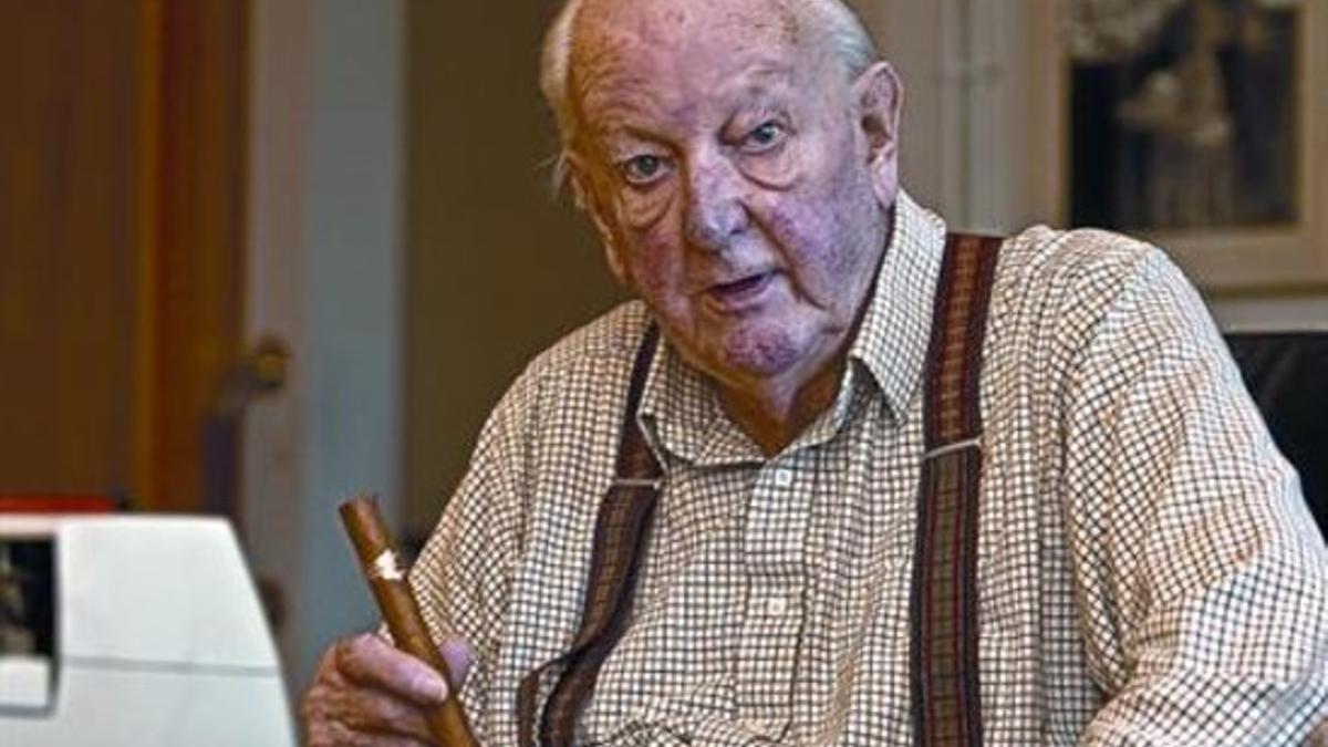 Tom Sharpe, en su casa de Llafranc, sentado frente a su máquina de escribir con un puro en la mano.