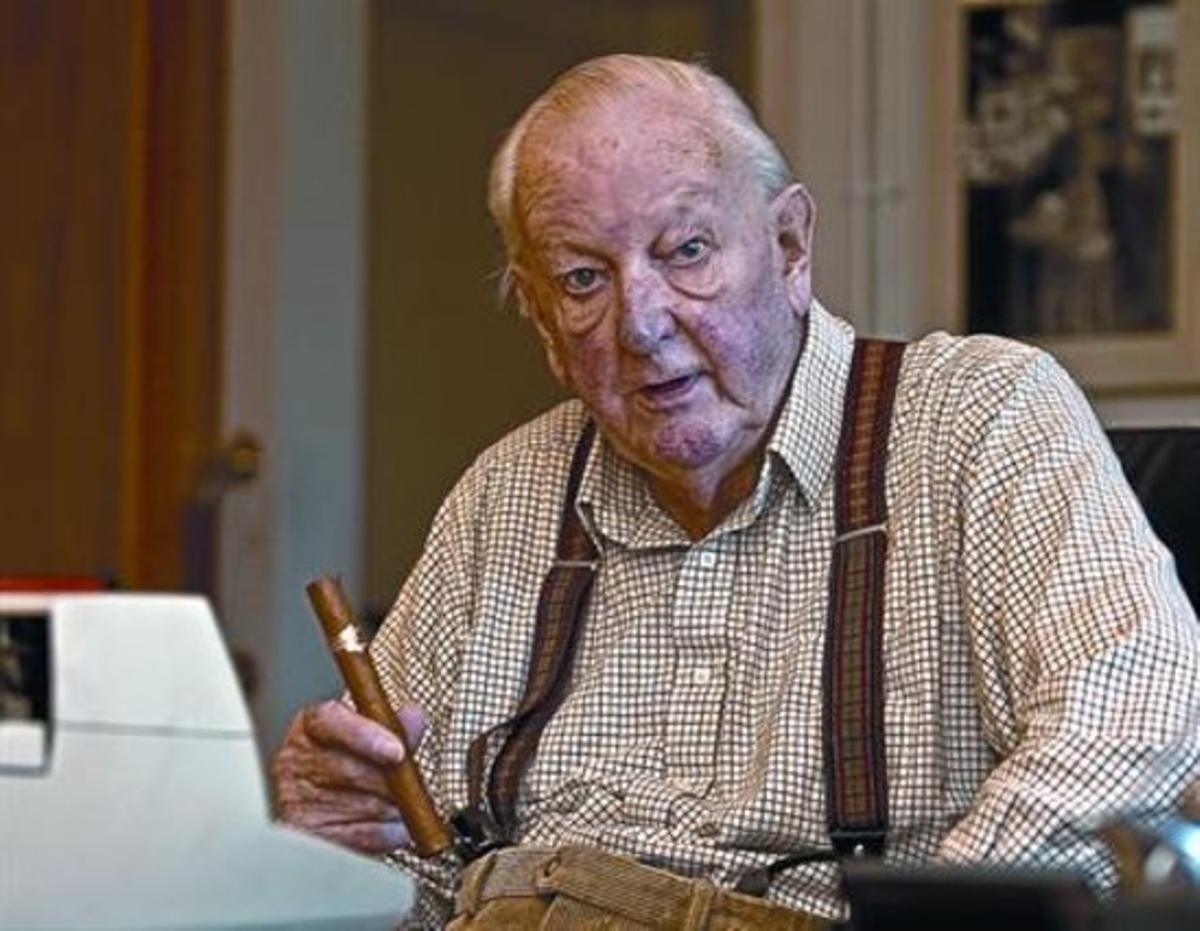 Tom Sharpe a la casa que té a Llafranc, assegut davant de la seva màquina d’escriure amb un puro a la mà.