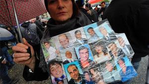 Una dona mostra fotos de familiars i amics morts de càncer, a Nàpols.