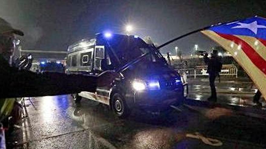 Un manifestant a Lledoners, davant del furgó que transporta els presos. Al costat, la caravana en direcció a Madrid.