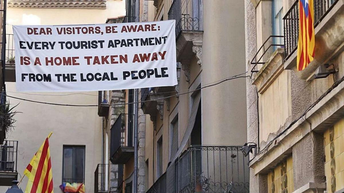 Una pancarta contra els pisos turístics adreçada als turistes, en una imatge d’arxiu.  | ACN