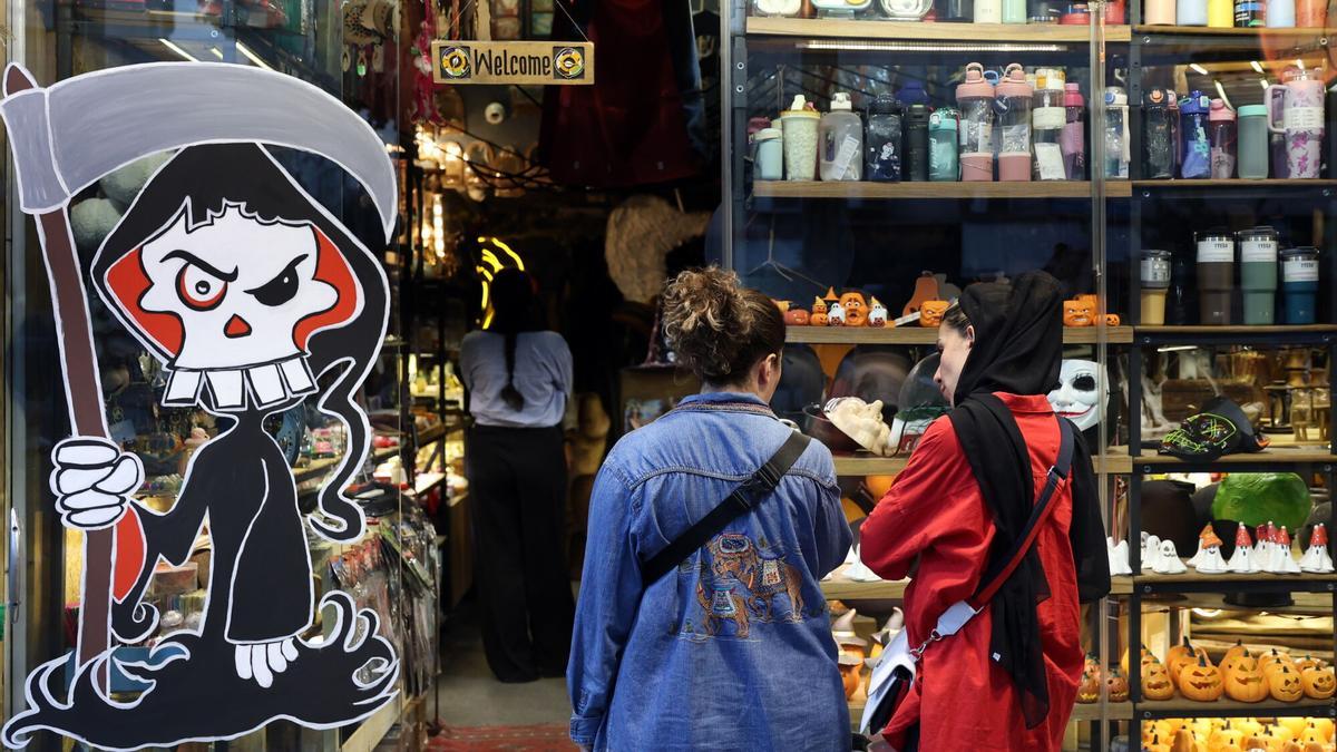 Dos mujeres, una sin velo, miran un escaparate con motivos de Halloween, el pasado 29 de octubre.