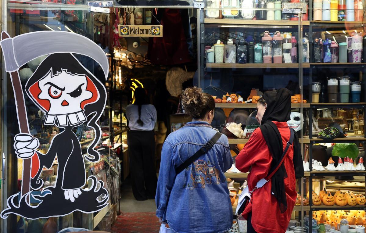 Dos mujeres, una sin velo, miran un escaparate con motivos de Halloween, el pasado 29 de octubre.